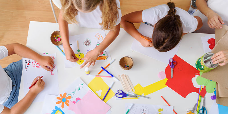 Children doing arts and crafts together on a table.